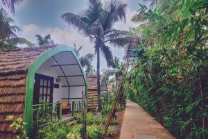 a house with a thatched roof and a walkway leading to a garden at Pause By The Sea in Morjim