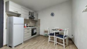 シラクーサにあるCasa Peloritaniのキッチン(白い冷蔵庫、テーブル、椅子付)