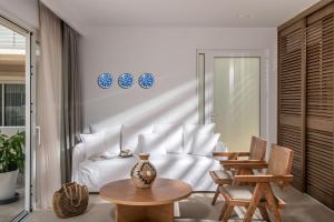een slaapkamer met een wit bed en een tafel en stoelen bij Aether by Nymphs residence II in Kókkinos Pírgos