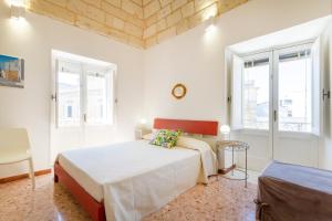 a white bedroom with a bed and two windows at Civico 22 B&B in Cannole