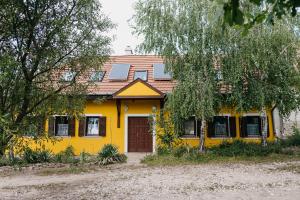 Casa amarilla con puerta y ventanas marrones en Hemina Vendégház, en Tata