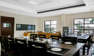 a dining room with tables and chairs and windows at Treebo Trend Little Budhha in Varanasi