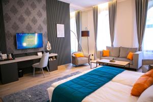 um quarto de hotel com uma cama, um sofá e uma televisão em House Of Charles em Carei