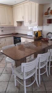 a kitchen with a counter with white chairs around it at Semi-Detached Villa in Vilamoura