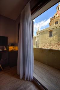 a window with a view of a building at Quaint Boutique Hotel Sannat in Sannat