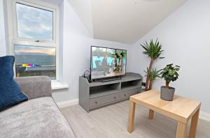 a living room with a couch and a tv at Entire penthouse apartment with sea views Portrush in Portrush