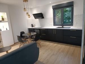 a kitchen with black cabinets and a table and chairs at Préstige in Rouilly-Sacey