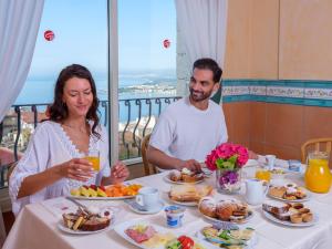 a man and a woman sitting at a table with breakfast at Hotel Ariston and Palazzo Santa Caterina in Taormina