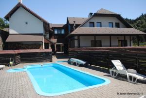 a swimming pool with two chairs and a house at Pension Karolína in Trnava