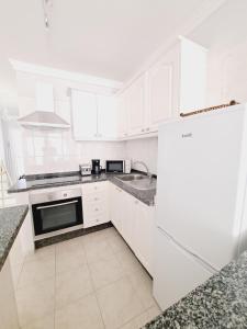 a white kitchen with a refrigerator and a sink at CANELA in Playa de San Juan