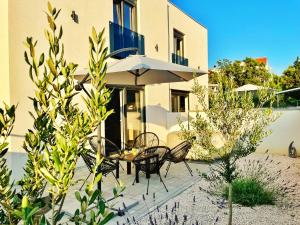 a patio with chairs and a table with an umbrella at Villa La Merion in Starigrad-Paklenica
