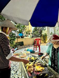 大叻的住宿－Villa - Hotel Nam Khang 2 Dalat，两个女人在伞下烤架上做饭