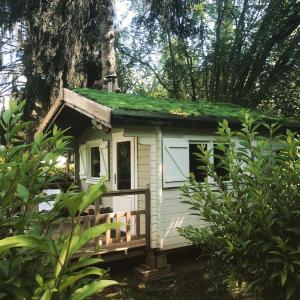 una pequeña casa blanca con techo de hierba en Arkeo - Luxury tents and cabins at the river, en Nonceveux