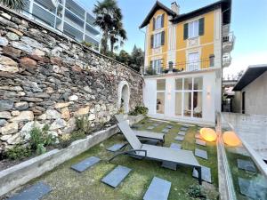 un patio con banco y pared de piedra en Tanja's Comfort Apartment Brissago, en Brissago