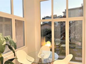 einen Glastisch und Stühle in einem Zimmer mit Fenstern in der Unterkunft Tanja's Comfort Apartment Brissago in Brissago