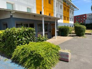 un bâtiment avec des buissons devant un bâtiment dans l'établissement Egg Hôtel Sarcelles, à Sarcelles