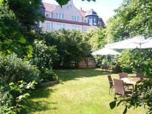 einen Garten mit einem Tisch, Stühlen und einem Sonnenschirm in der Unterkunft Hotel Hollerbusch in Weimar