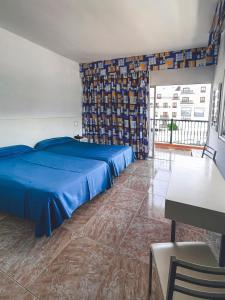 a bedroom with a blue bed and a table at Apartamentos Chinyero in Puerto de la Cruz