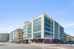 Un edificio alto y blanco en una calle de la ciudad. en Modern, mooi en stijlvol app vlakbij winkelstraat, en Knokke-Heist