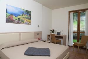 a hotel room with a bed, table, and window at Appartamenti Corte Leonardo in Garda