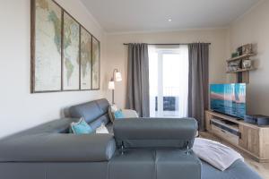a living room with a blue couch and a flat screen tv at Penthouse SeeZeichen mit Seeblick in Nordstrand