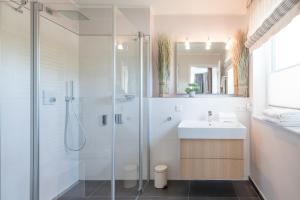 a bathroom with a glass shower and a sink at Penthouse SeeZeichen mit Seeblick in Nordstrand +15 photos