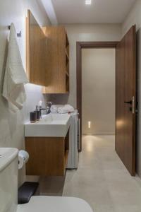 ein Bad mit einem Waschbecken, einem WC und einer Tür in der Unterkunft Athena Apartment in Iraklio