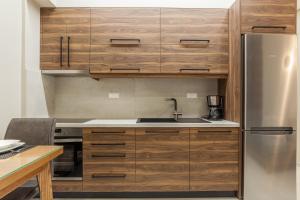 een keuken met houten kasten en een roestvrijstalen koelkast bij Athena Apartment in Heraklion