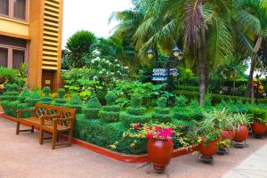 Coconut Grove Regency Hotel في آكرا: حديقة فيها جلسة و ورد و نباتات