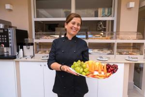 a woman holding a plate of fruit and vegetables at ELISEO PALACE TROPEA in Tropea