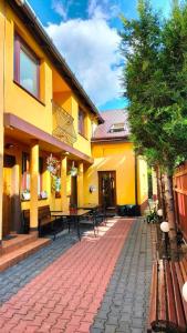 a yellow building with a patio with tables and chairs at Pokoje u Eli in Szczawnica