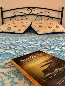 a book sitting on top of a bed with two pillows at Adega do Golfinho in Feiteira