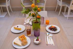 a table with plates of food and a vase with oranges at ELISEO PALACE TROPEA in Tropea