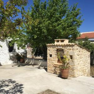 Kórinthos的住宿－Aνεξάρτητη παραδοσιακή πέτρινη κατοικία，一座石头建筑,房子前面有一棵树