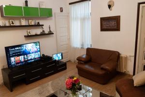 a living room with a flat screen tv and a chair at Casa Ferdinand in Constanţa
