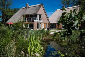 une maison avec un étang en face de celle-ci dans l'établissement Residenz - Himmelsträumer - Penthouse - Sauna - Parkplatz, à Bad Zwischenahn