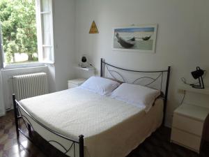 una camera da letto con un letto con lenzuola bianche e due finestre di Piccolo Lago a Travedona