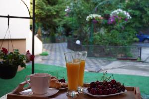 a tray with two glasses of orange juice and a plate of cherries at Casa Ferdinand in Constanţa