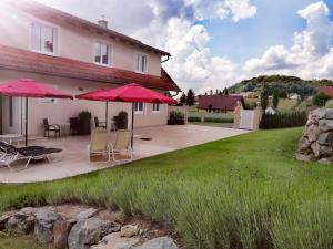 a patio with chairs and umbrellas in front of a house at Landhaus Stenitzer 