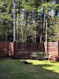 a wooden fence with a table and chairs in a yard at Maren's apartment on Randbøl Heath in Randbøl