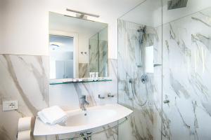 een witte badkamer met een wastafel en een douche bij Hotel Gorini in Bellaria-Igea Marina