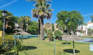 un parque con sombrillas y una piscina en Apto Aldea del Coto, en Chiclana de la Frontera