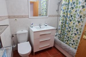 Un baño con inodoro, lavabo y cortina de ducha. en Apto Aldea del Coto, en Chiclana de la Frontera