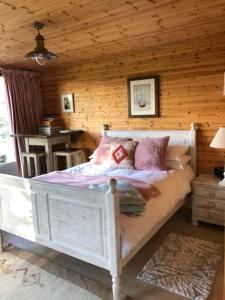 a bedroom with a white bed in a log cabin at Self Contained Garden Studio with stunning views in Sissinghurst