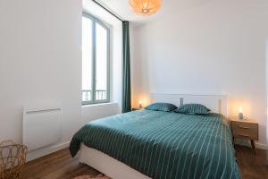a white bedroom with a green bed and a window at Appartements centre-ville - Wifi - Cuisine tout équipée - Lave-linge in Pau