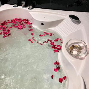 a bath tub filled with red flowers in a sink at Peacock Pool Villa in Nong Prue