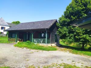 a small house with a porch in a yard at Chalet bois in Neuville