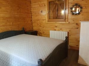 1 dormitorio con 1 cama en una cabaña de madera en SUPERBE CHALET AVEC PISCINE CHAUFFEE Juillet et Aout, en Saint-Manvieu-Bocage