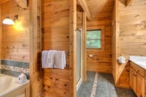 a log cabin bathroom with a tub and a sink at RiverStone Condo Resort & Spa in Pigeon Forge