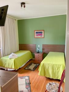 two beds in a room with green walls at Hotel Uruguay Brasil in Rivera